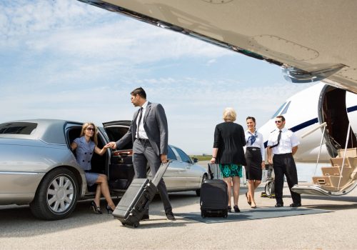 Business partners about to board private jet while airhostess and pilot greeting them
